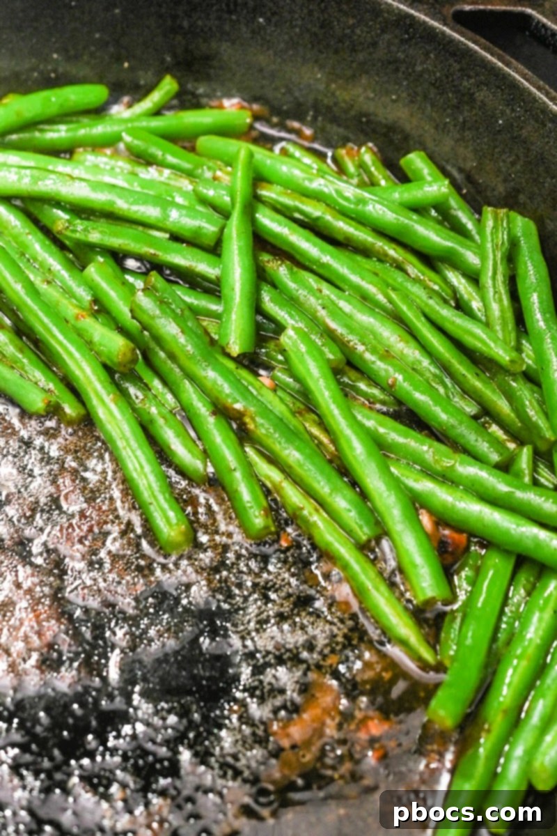 Keto Honey Garlic Chicken with Green Beans 10 Fresh green beans being stirred into chicken broth in a skillet.