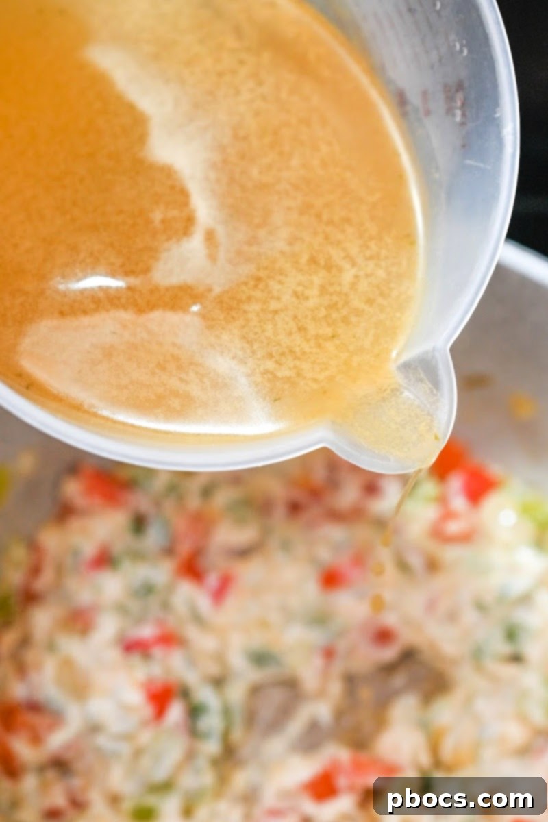 Pouring chicken broth into the soup pot