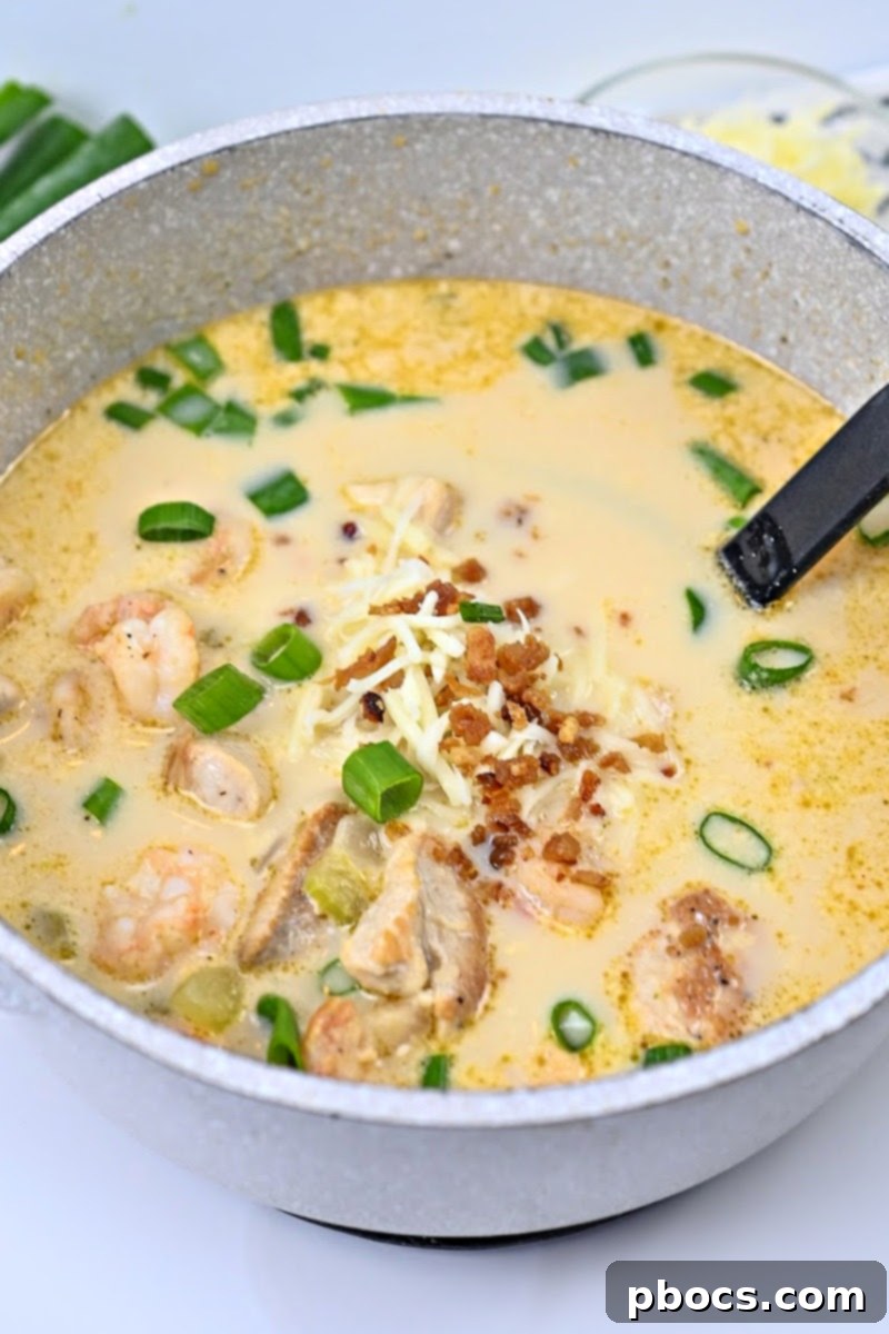 Serving Keto Cajun Chicken & Shrimp Soup garnished with cheese, green onions, and bacon