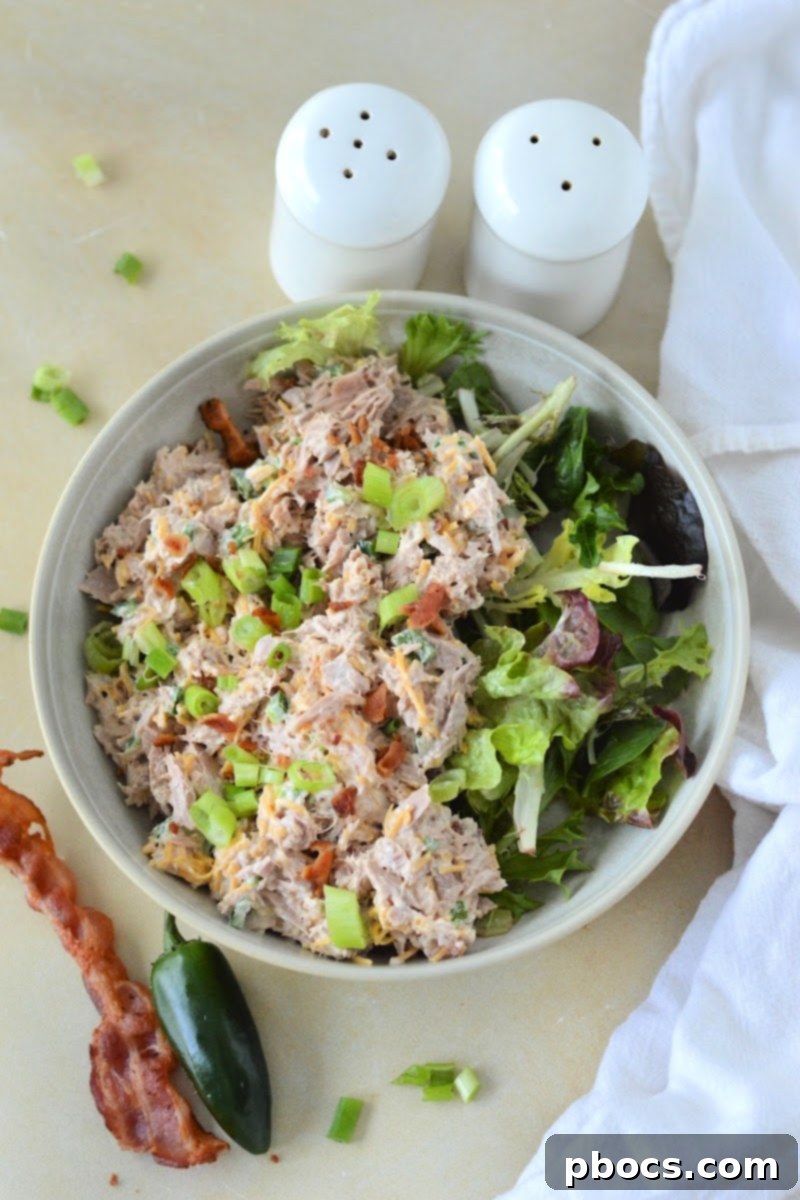 A close-up view of the creamy texture of Keto Jalapeno Popper Tuna Salad, with visible jalapeno pieces and green onions