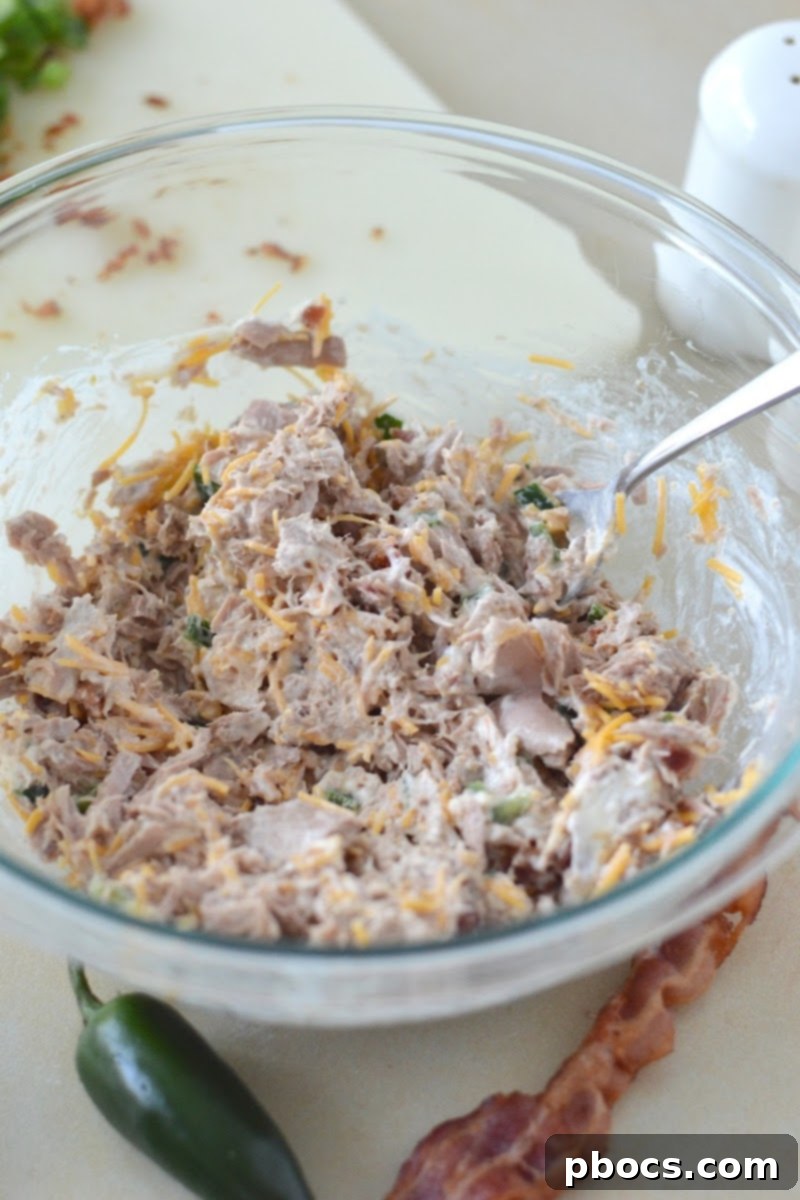 A serving of Keto Jalapeno Popper Tuna Salad presented beautifully in a bowl, topped with crispy bacon bits and green onions