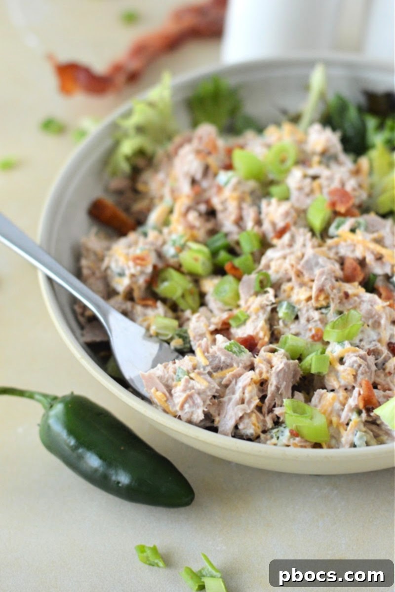 Keto Jalapeno Popper Tuna Salad artfully arranged on a large lettuce leaf, accompanied by slices of keto cloud bread