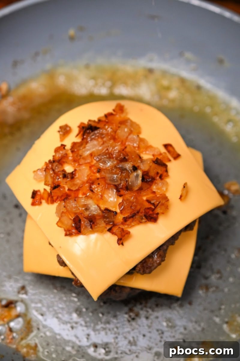 Adding sautéed onions on top of the cheese and burger stack