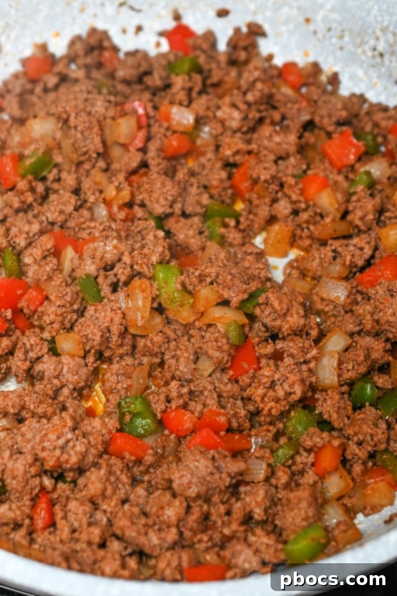 Seasoning sprinkled over meat mixture in skillet