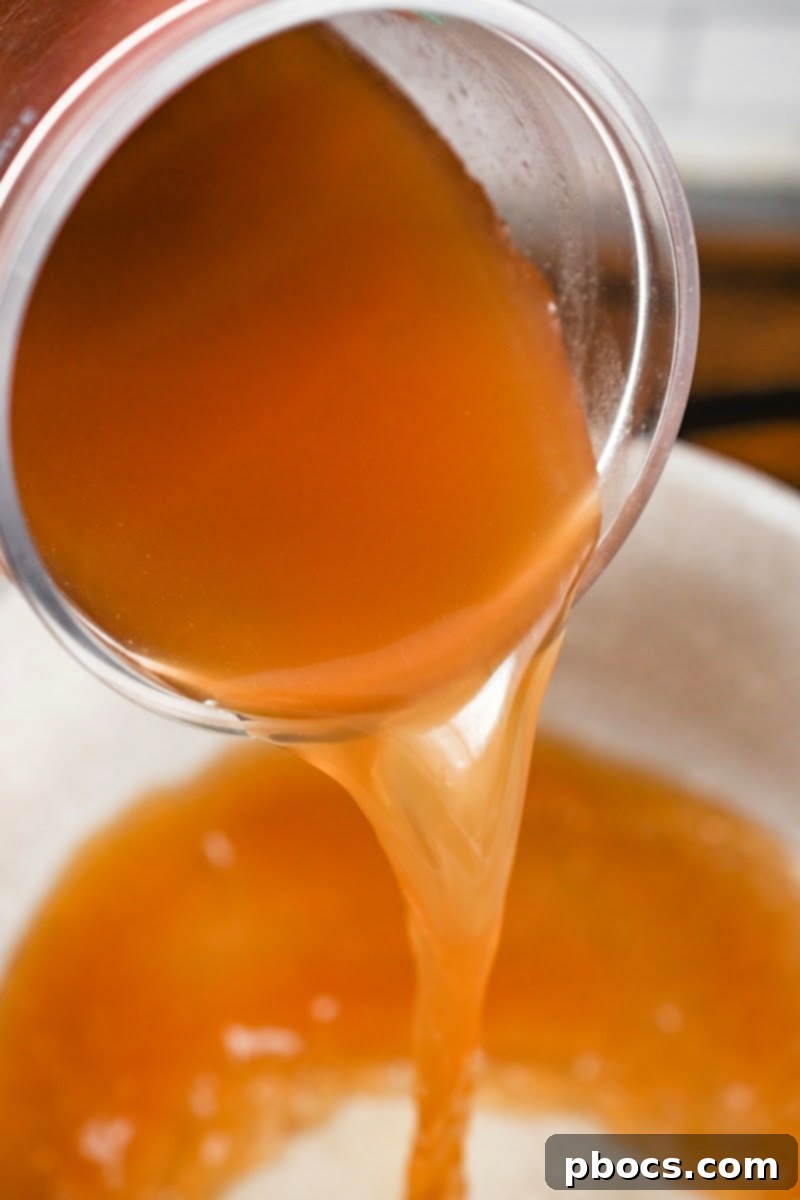Beef broth being poured into a pot for the pho