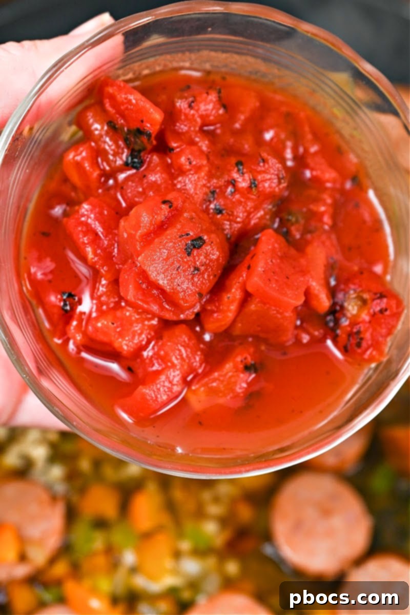 Adding chicken broth and diced tomatoes to the skillet mixture.