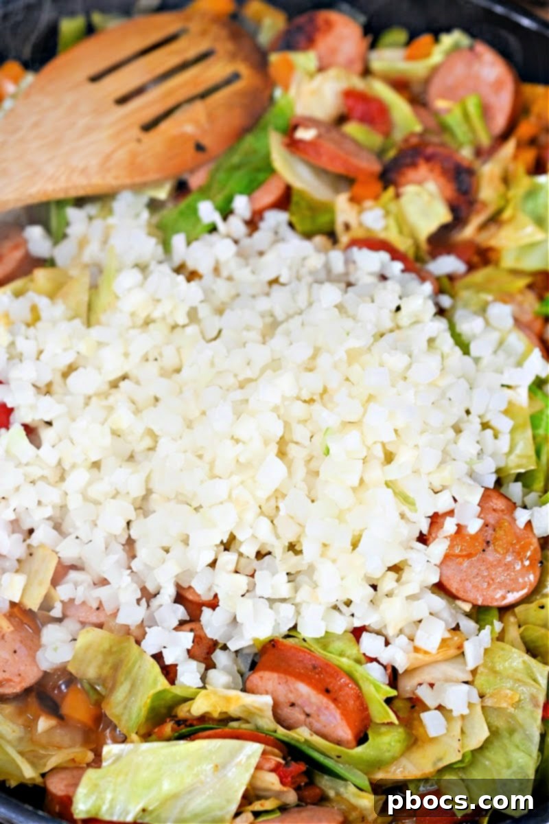 Adding cooked cauliflower rice to the Keto Cabbage Jambalaya Skillet.