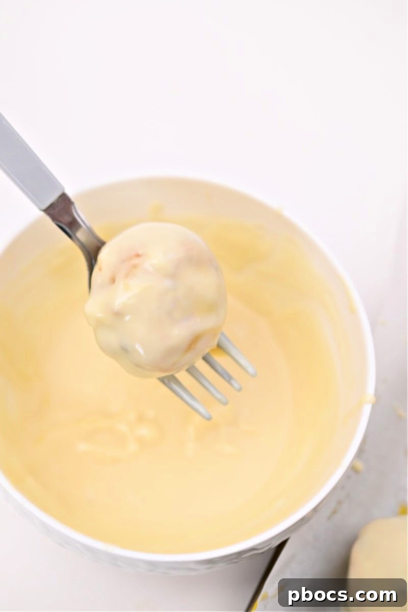 Dipping a carrot cake ball into melted white chocolate