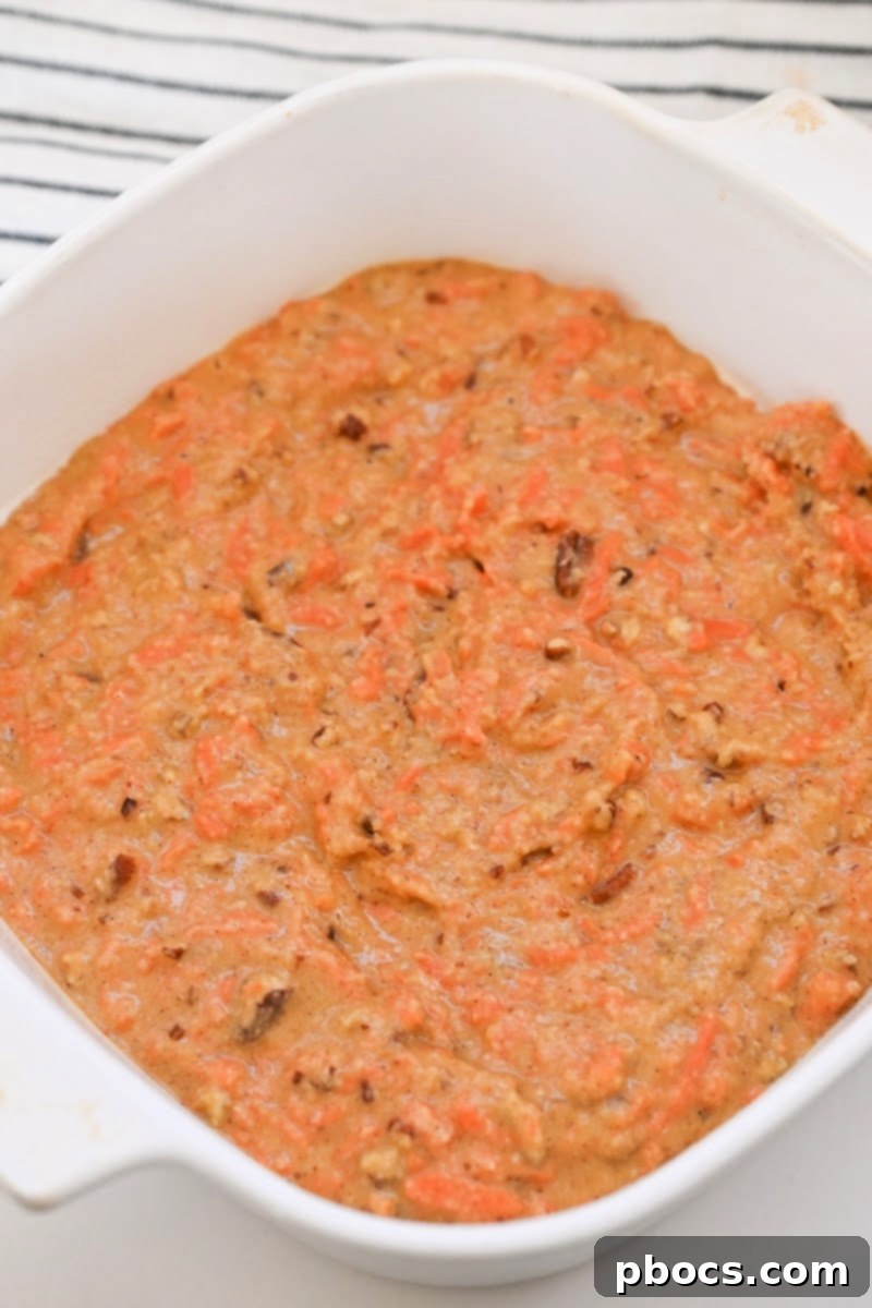 Unbaked carrot cake batter spread in a square pan