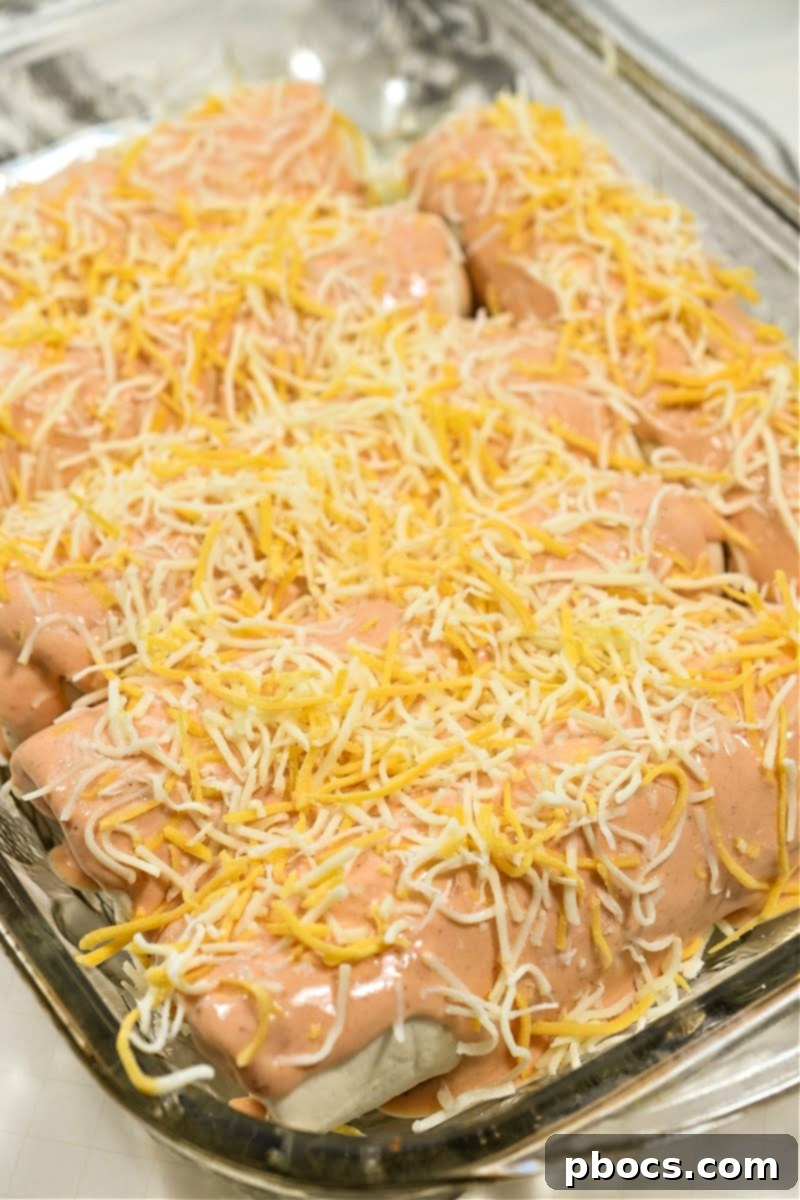 Adding cheese on top of Keto Crack Chicken Enchiladas before baking