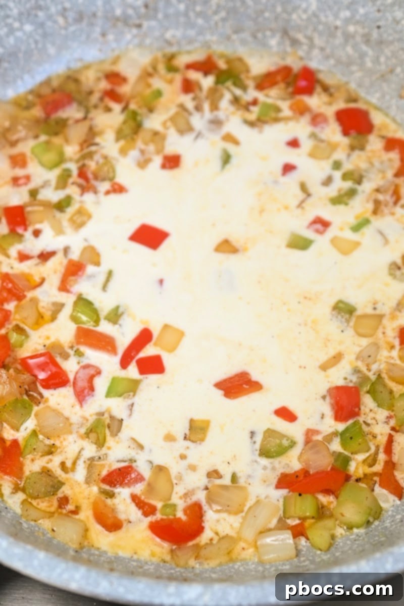 Adding heavy cream to the skillet for Cajun Alfredo sauce