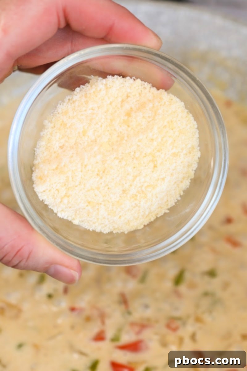Grated Parmesan cheese being added to the Cajun Alfredo sauce