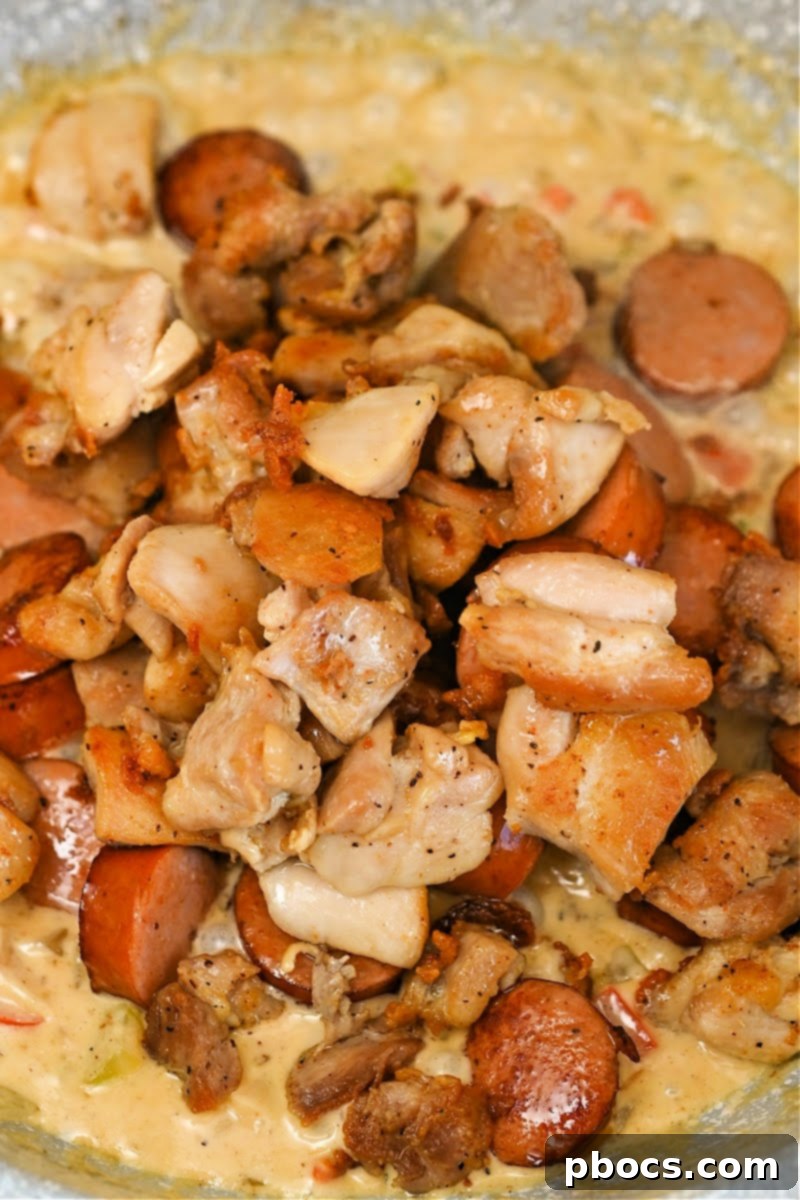 Returning cooked chicken to the Cajun Alfredo skillet