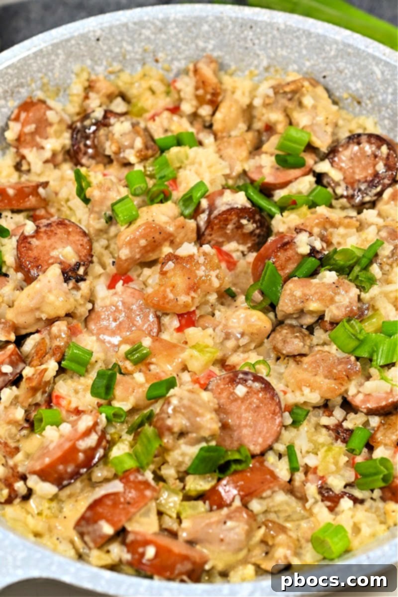 Sliced Andouille sausage and chicken cooking in a skillet for Cajun Alfredo