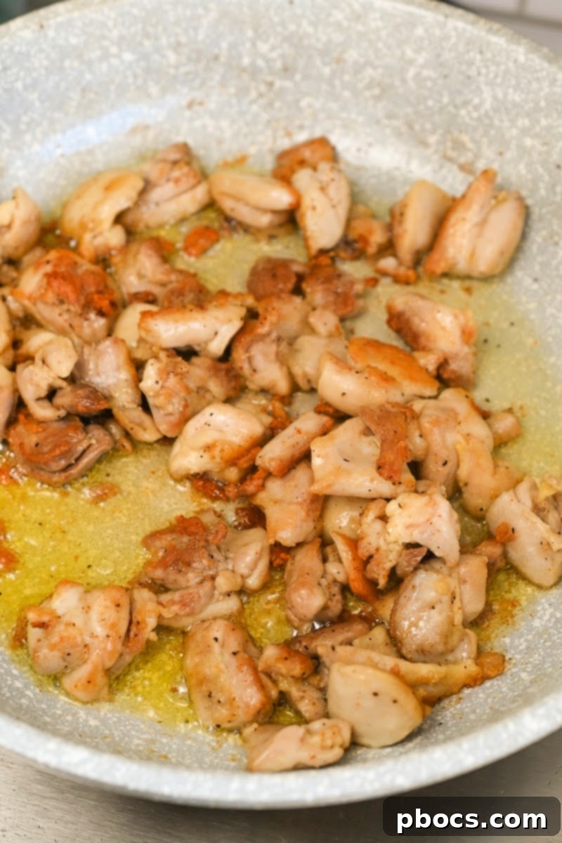 Cooking chicken in a skillet for Keto Cajun Alfredo