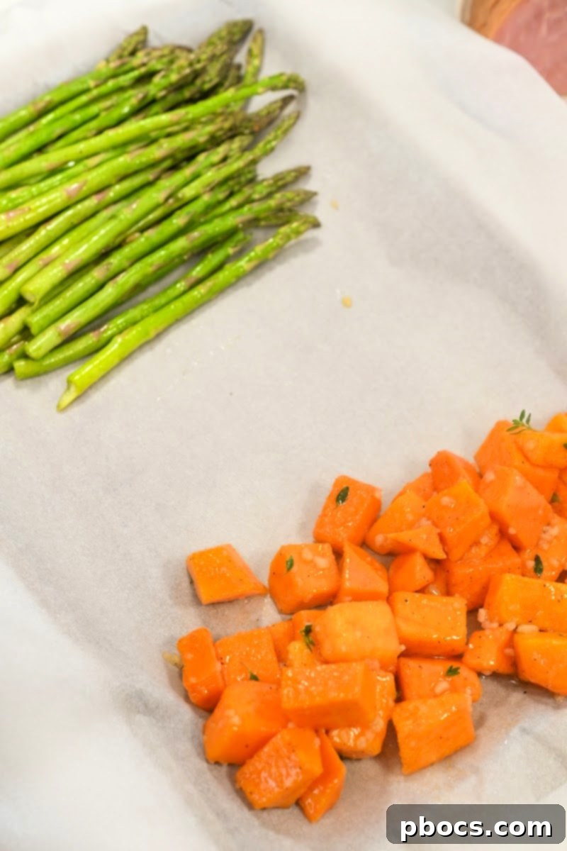 Adding seasoned asparagus and butternut squash to the sheet pan