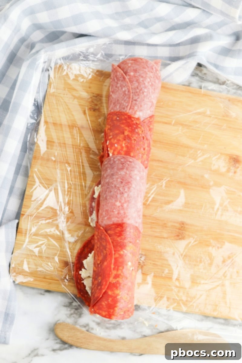 Third step of Keto Boursin Roll Ups: Spreading the creamy Boursin cheese evenly over the cured meat base.