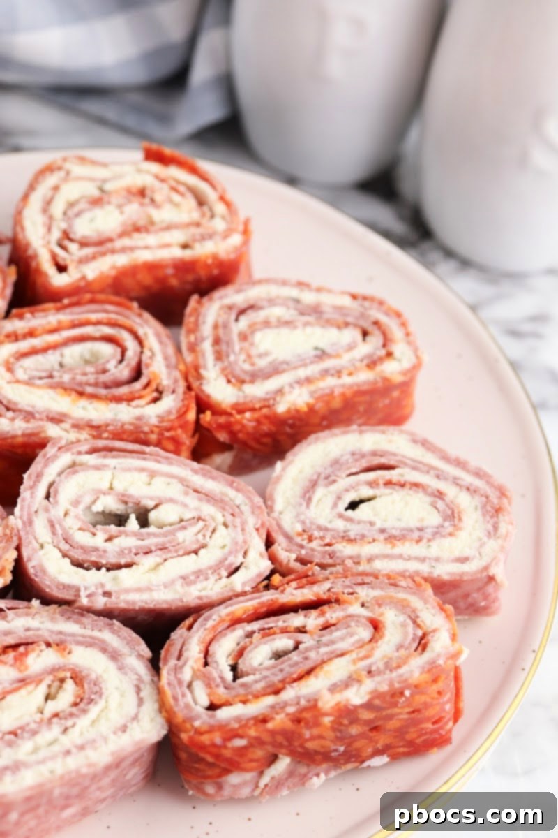 Various ingredients for Keto Boursin Roll Ups laid out, showing the creamy Boursin cheese, deli salami, and pepperoni slices.