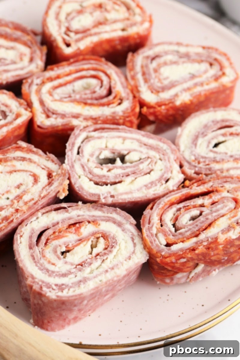 A close-up of a partially prepared Keto Boursin Roll Up, showing the cheese spread over a layer of cured meats before rolling.