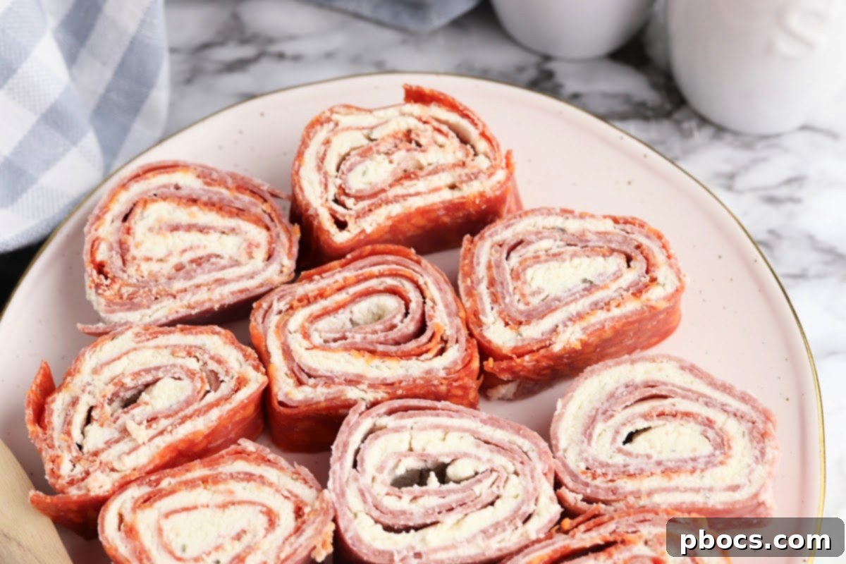 A tightly rolled log of Keto Boursin Roll Ups, wrapped in plastic wrap, indicating proper storage before slicing.