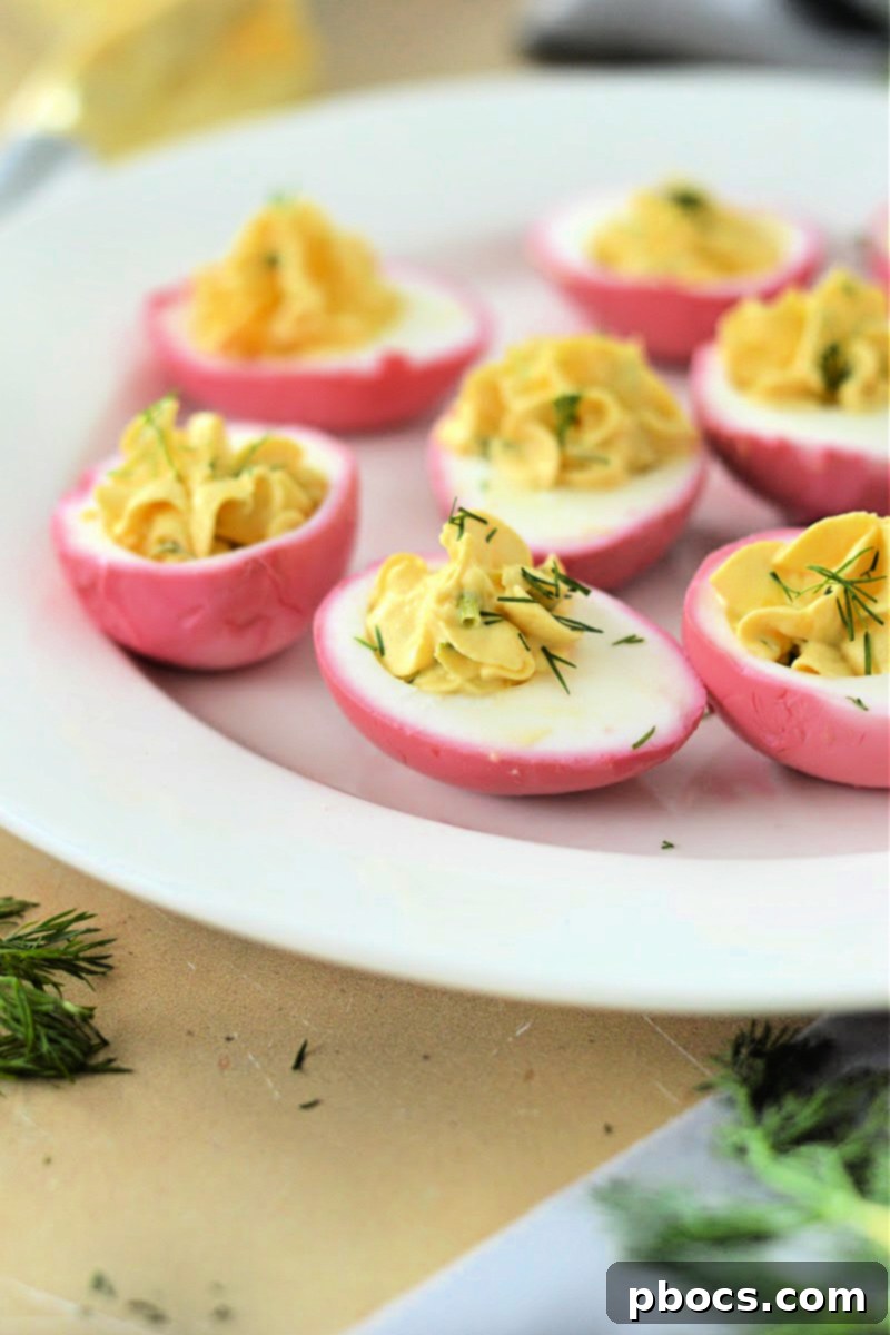 Vibrant Pink Keto Pickled Deviled Eggs arranged on a plate