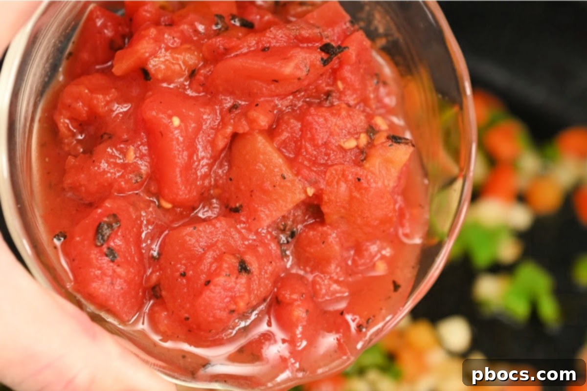 Fire roasted tomatoes and chicken broth being added to the skillet