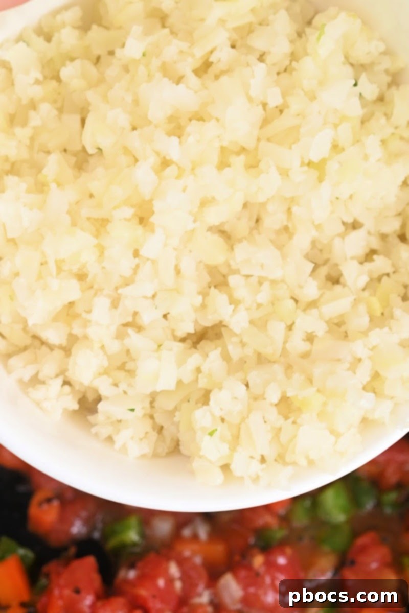 Cauliflower rice being added to the skillet
