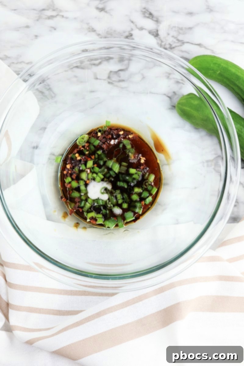 Vibrant Korean Cucumber Salad 9 Step-by-step image showing red pepper flakes, sweetener, oils, garlic, soy sauce, and rice vinegar being whisked in a bowl to create the dressing