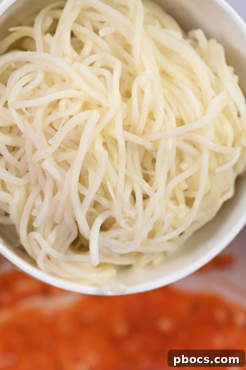 Palmini noodles being stirred into the marinara and cottage cheese mixture