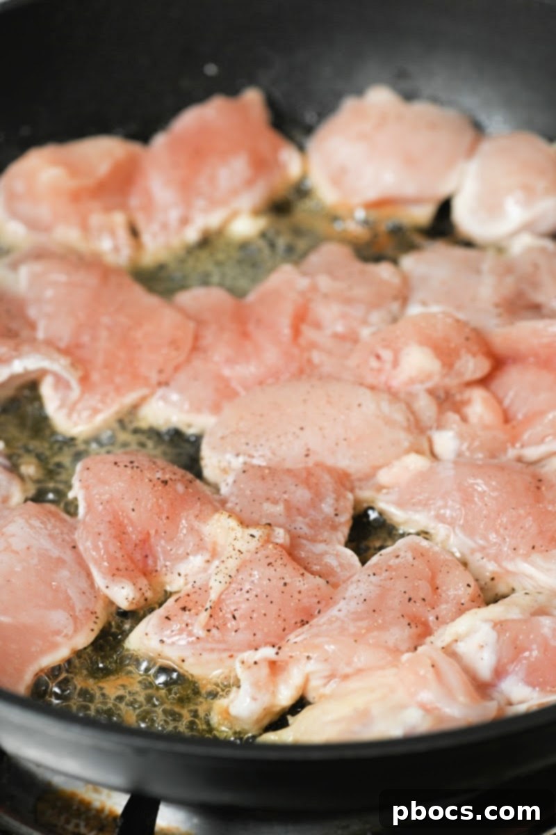 Diced chicken breast pieces searing in butter in a skillet