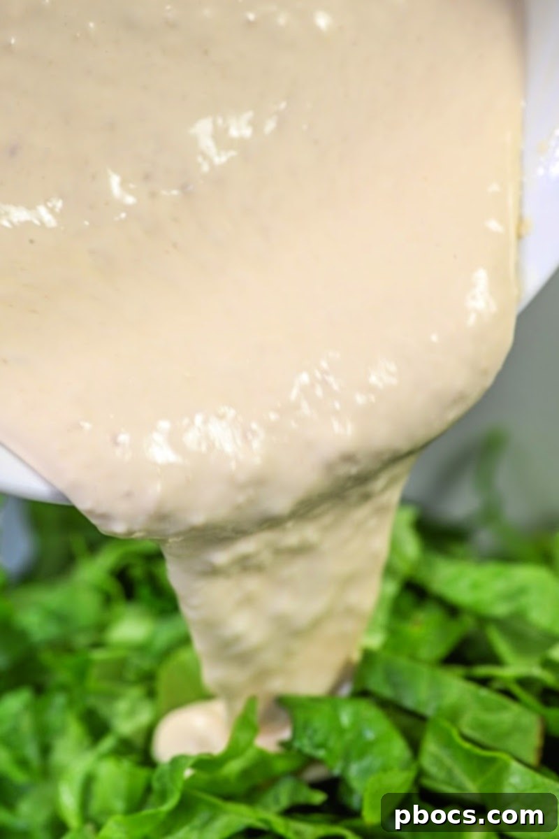 Keto Broccoli Caesar Crunch 10 Pouring homemade Caesar dressing over a mixture of broccoli and romaine lettuce