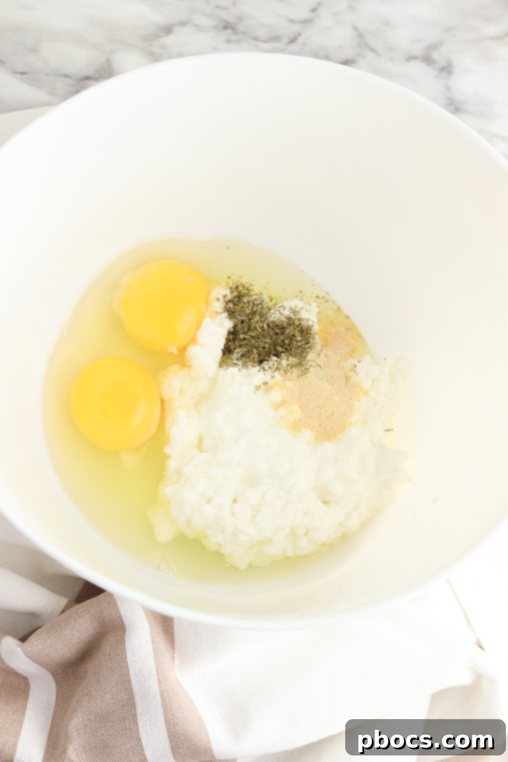 Mixing cottage cheese, eggs, and seasonings in a bowl