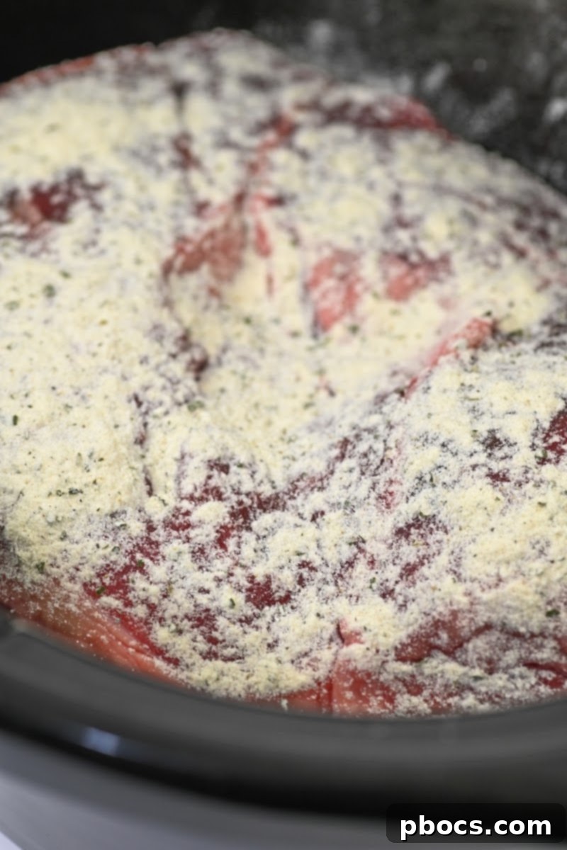 Sprinkling dry ranch seasoning on top of the meat