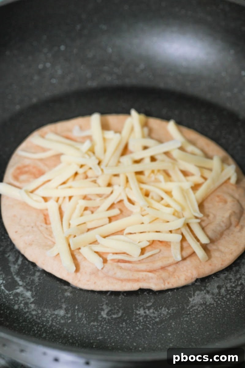 Adding cheese to the tortilla in a skillet