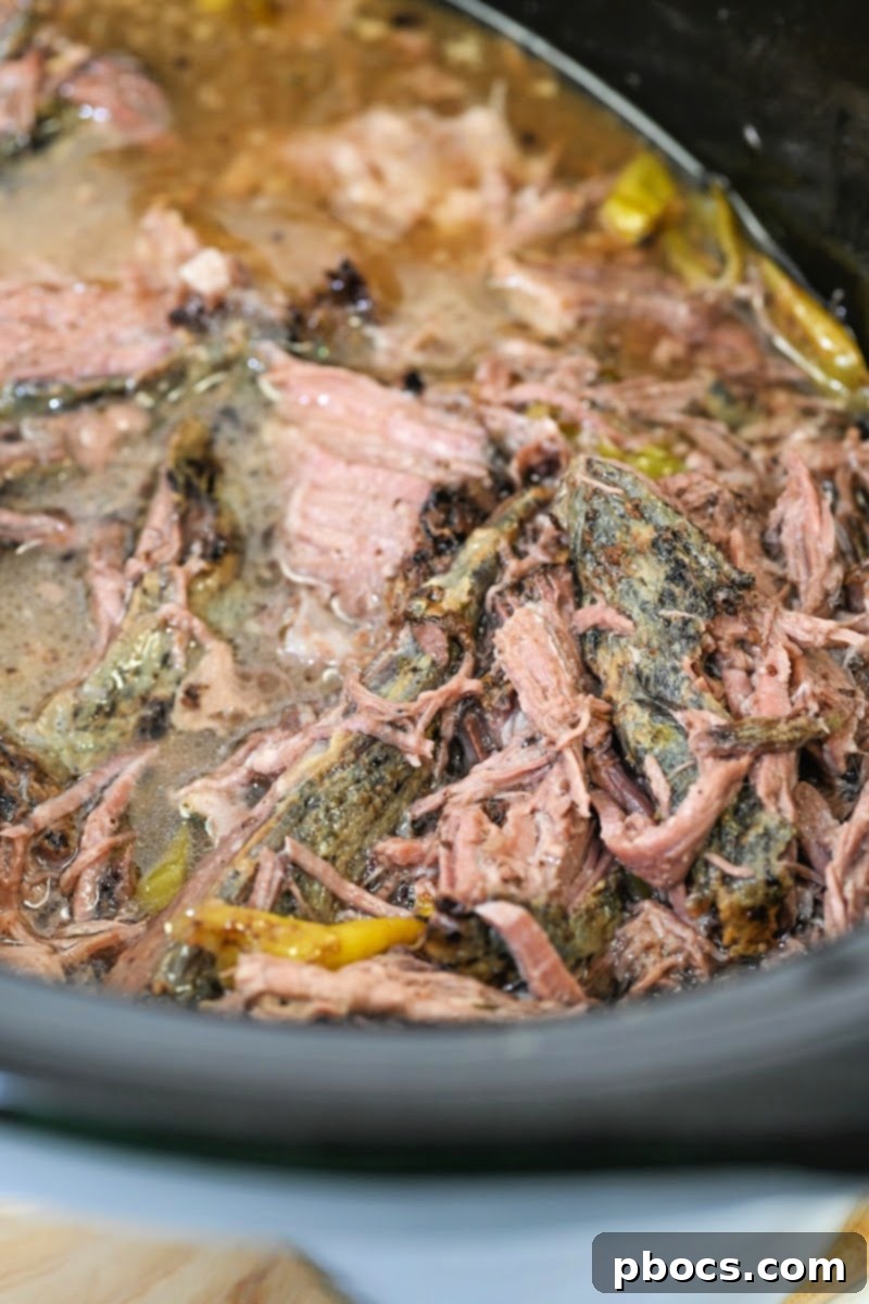 Cooked Mississippi Pot Roast in a slow cooker, ready for shredding