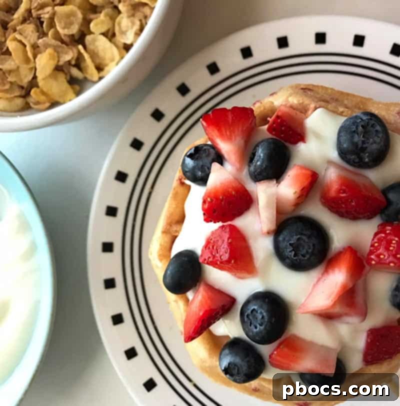 Breakfast Waffle Cake topped with fruit, yogurt, cereal, and syrup