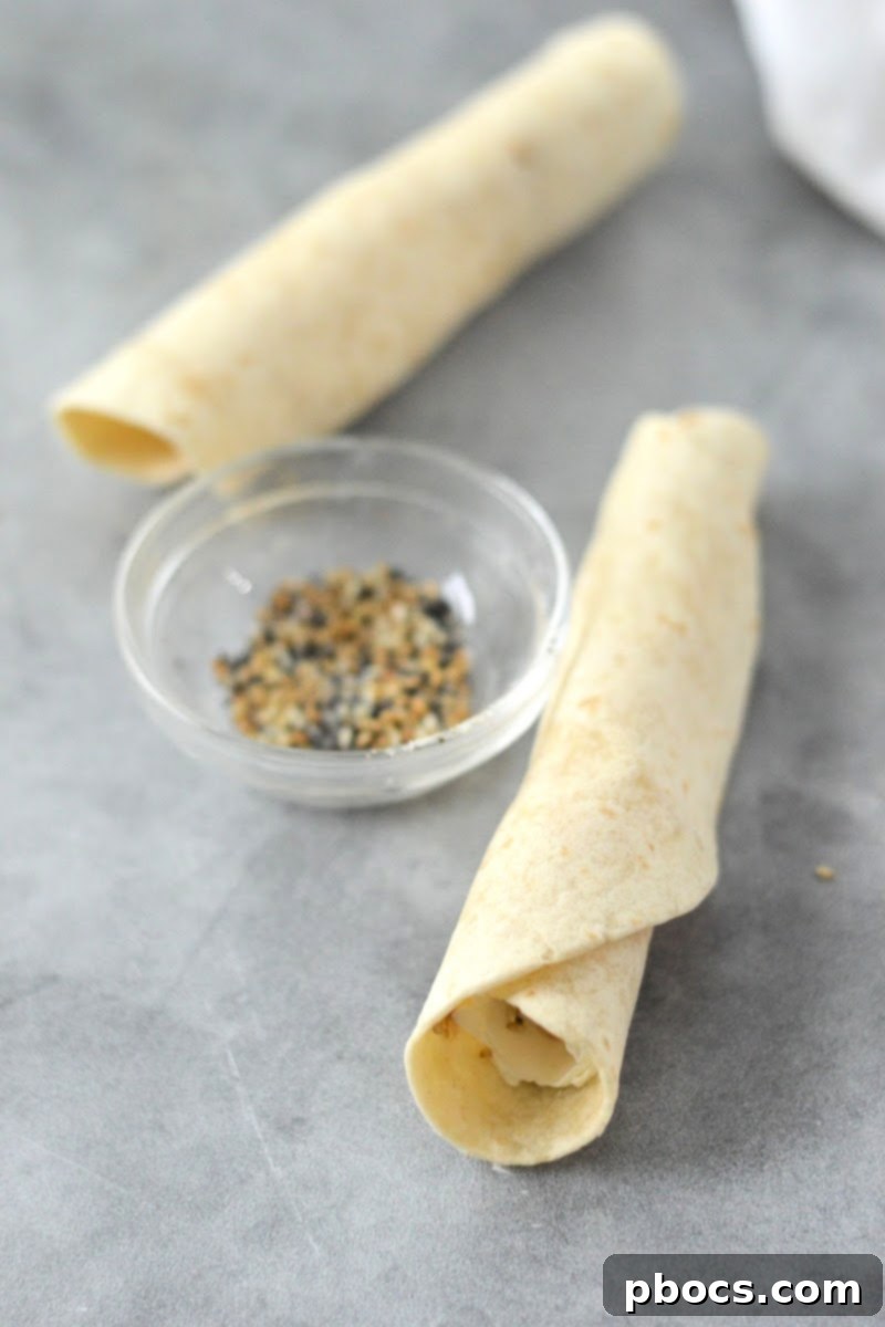 Keto Cream Cheese Bagel Poppers 11 Step 3: Tightly rolling the cream cheese and seasoning-filled tortilla into a compact log.