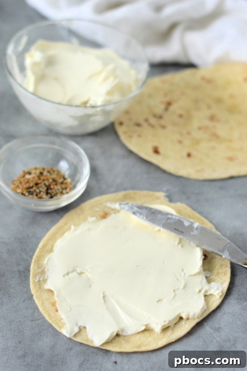 Keto Cream Cheese Bagel Poppers 9 Step 1: Spreading softened cream cheese evenly over a low-carb tortilla.