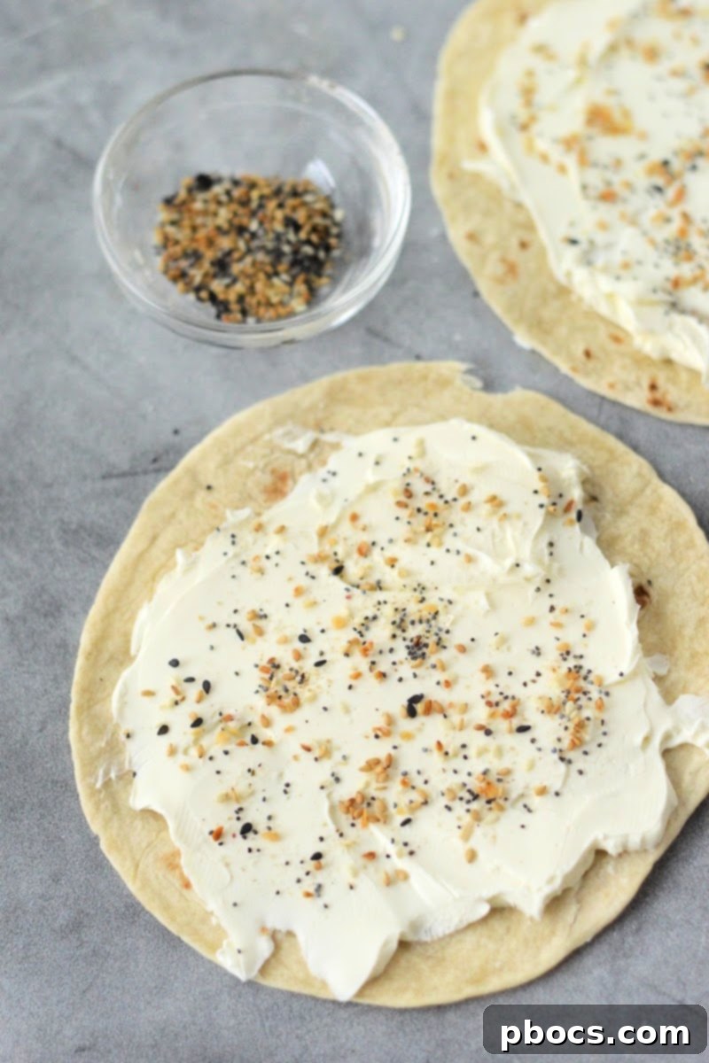 Keto Cream Cheese Bagel Poppers 10 Step 2: Sprinkling Everything Bagel Seasoning generously over the cream cheese-covered tortilla.