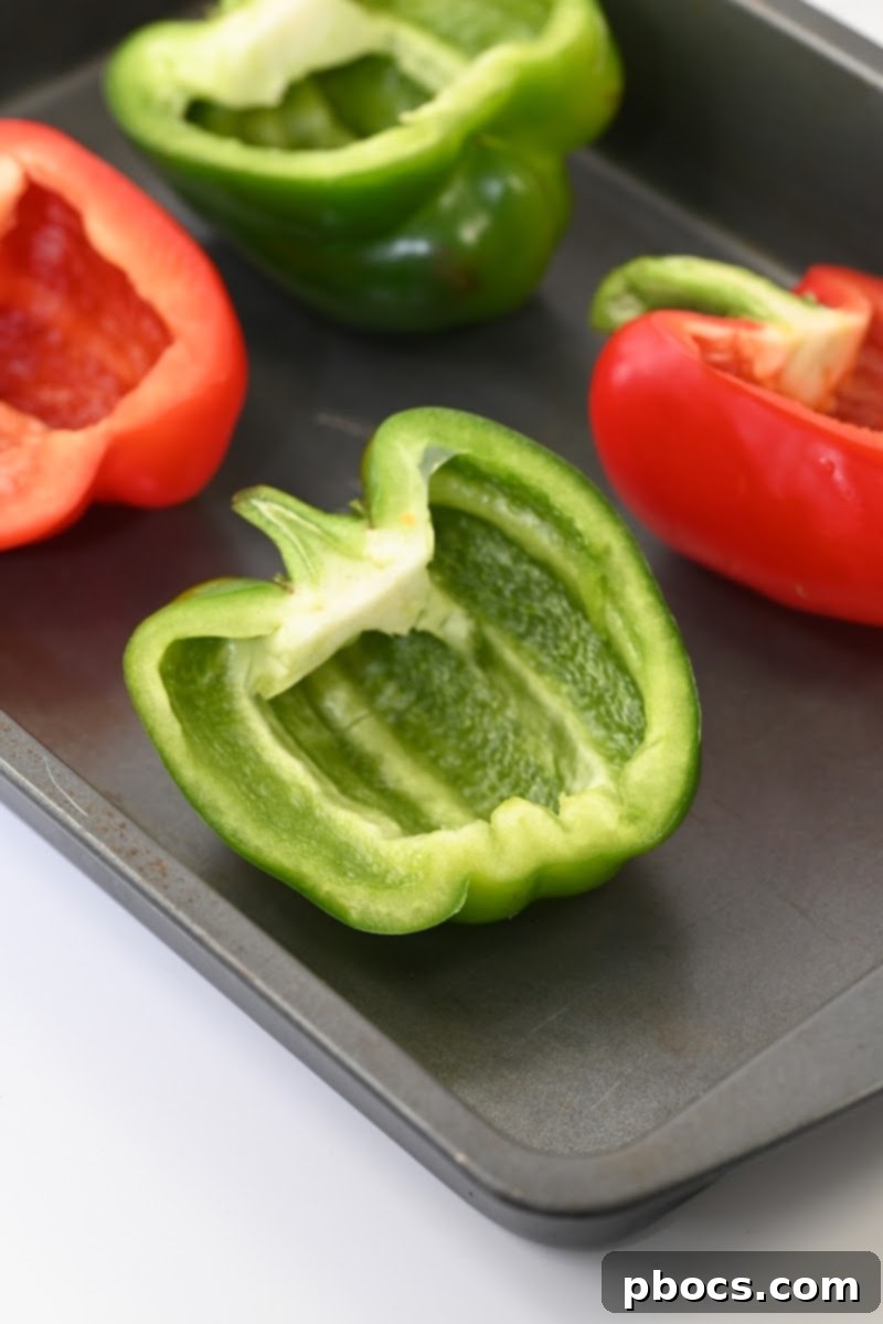 Halved red and green bell peppers on a baking sheet