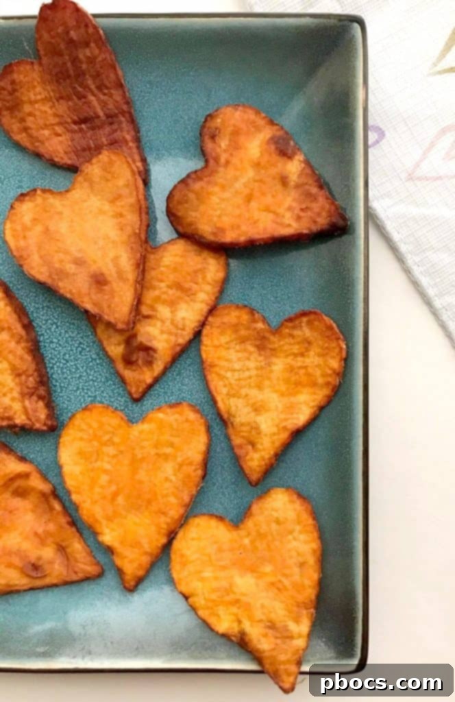 Heart-shaped sweet potato slices baking on a sheet pan, halfway through cooking.