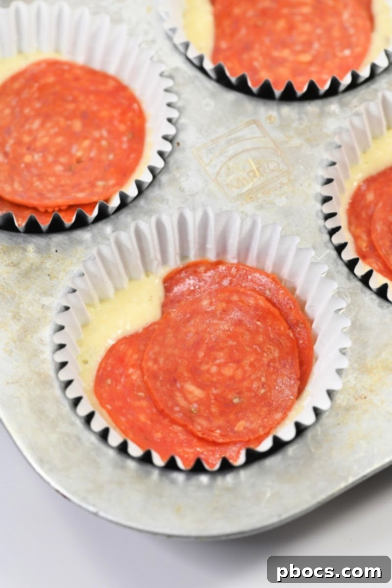 Keto Pizza Poppers 12 Adding pepperoni slices to the muffin batter