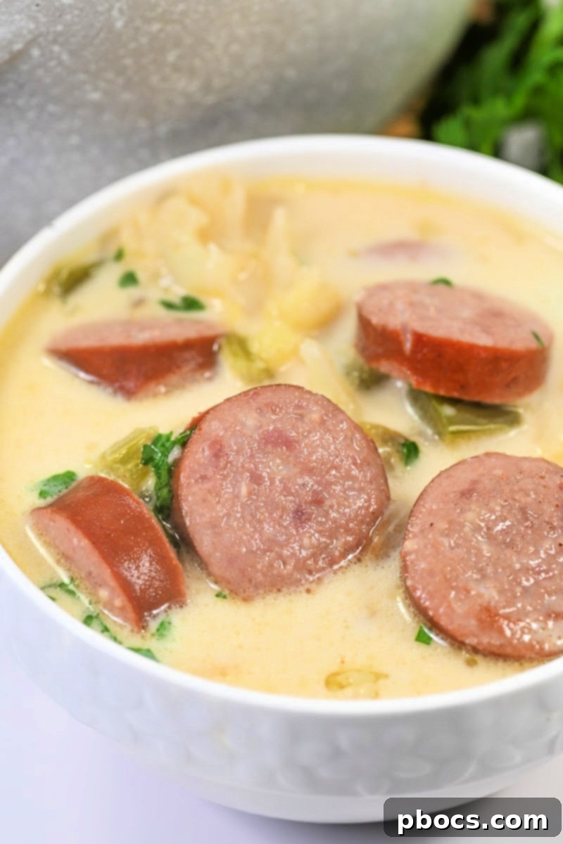 Rich and creamy Keto Creamy Kielbasa and Cauliflower Soup, garnished with fresh herbs in a rustic bowl