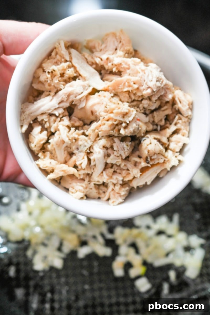 Shredded chicken being added to the skillet