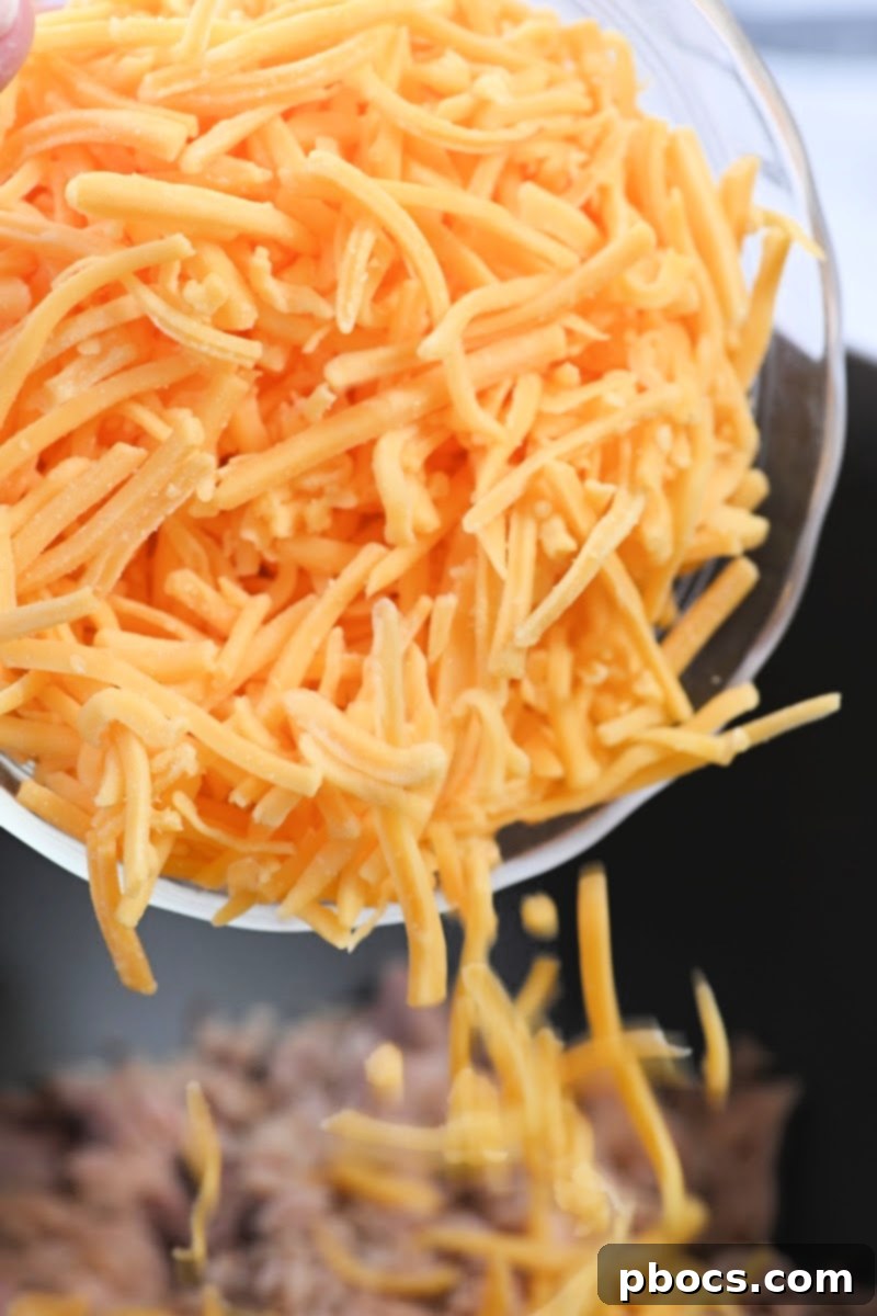 Mixing bowl with shredded cheddar cheese being added