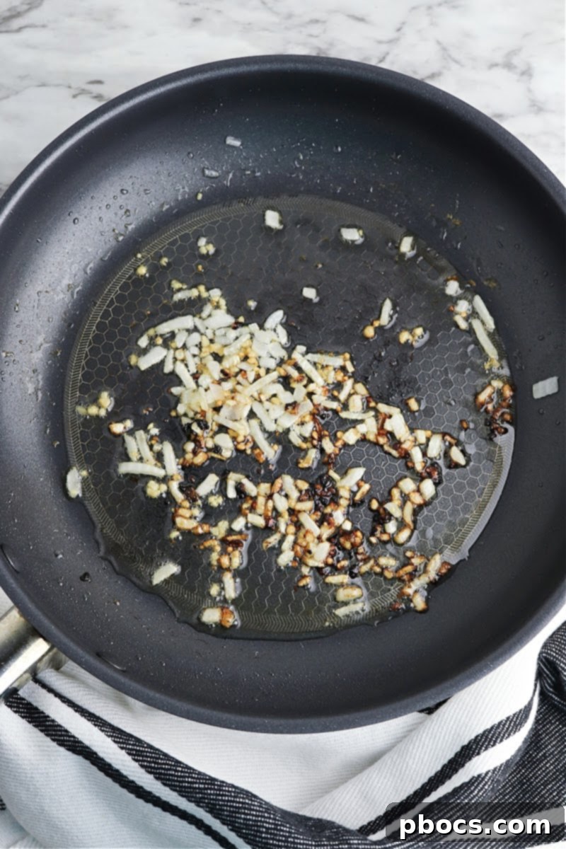 Mediterranean Keto Spinach Feta Bake 11 Sautéing garlic in a skillet.