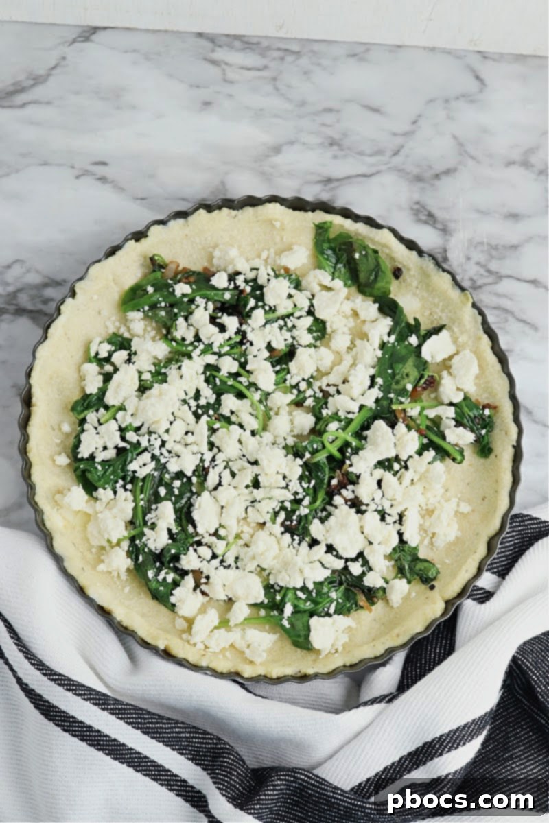 Mediterranean Keto Spinach Feta Bake 13 Adding crumbled feta cheese to the quiche filling.