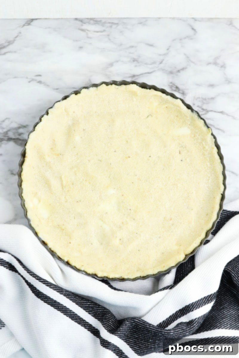 Mediterranean Keto Spinach Feta Bake 10 Preparing the keto quiche crust in a pan.