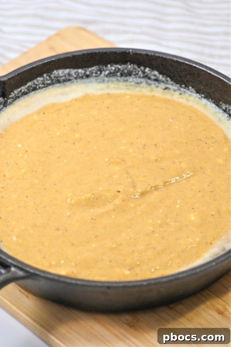 Pouring Keto Pumpkin Spice Dutch Baby batter into the hot cast iron skillet