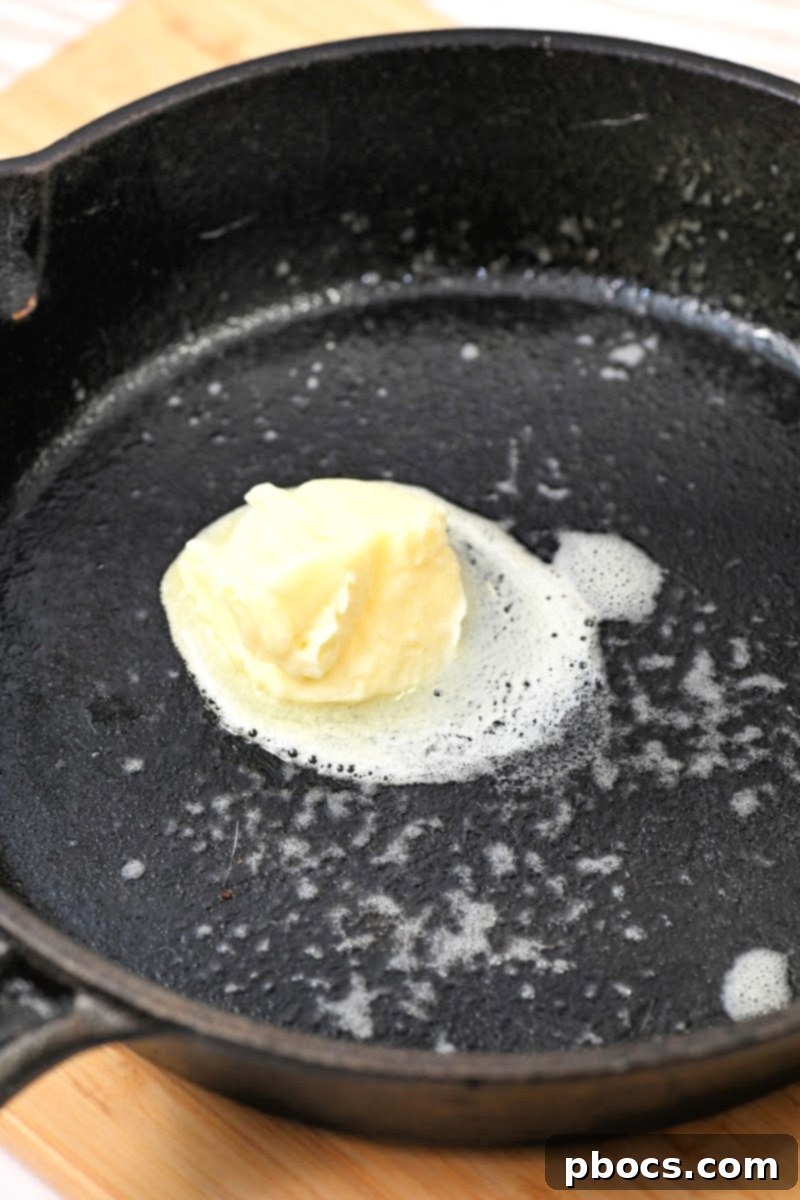 Melting butter in the preheated cast iron skillet for Dutch Baby